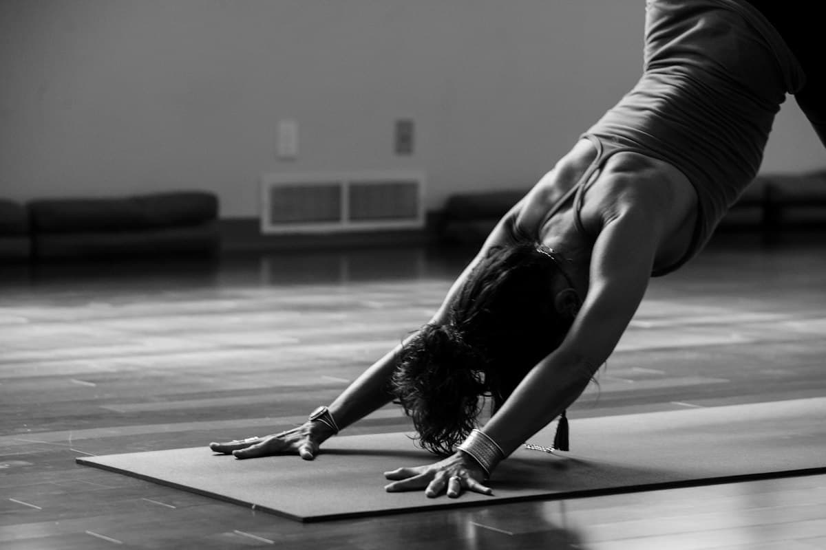 Teacher holding downward-facing dog on a dark studio floor