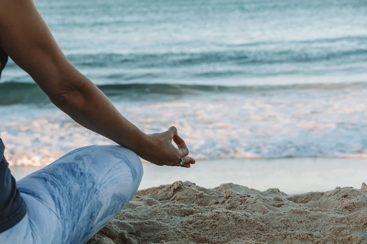 Teacher resting hands in mudra beside the ocean