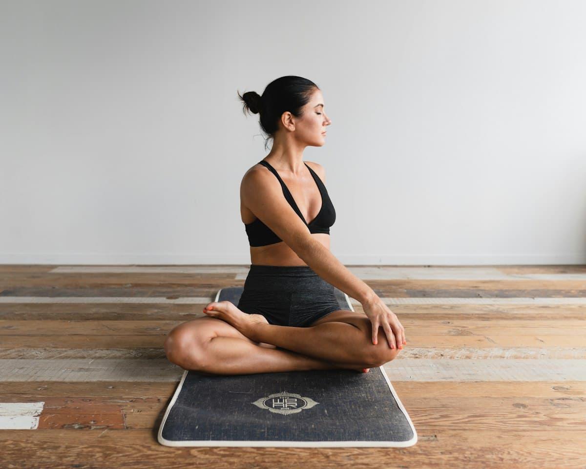 Woman seated cross-legged on a mat in a bright studio